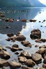 Peaceful scene of stones in the mirror like lake water with mountain reflection, Tysdalsvatnet, summer Norway, travel experience