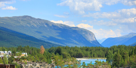 overlook the sapphire blue Dønfoss river in the forest with nordic mountain in the background in summer Norway, E6 road landscape