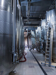 Wine production. Steel vats on winery territory. Workshop with new large fermentation tanks. Modern bio vine industry. Production room at the winemaking factory. Industrial equipment for alcohol.