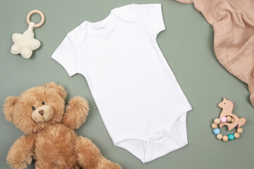 White children bodysuit onesie mock up and kid toys on green background with white and brown cotton...