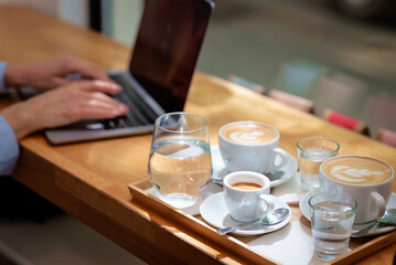 Close-up of female hand typin gon laptop keyboard at the cafe