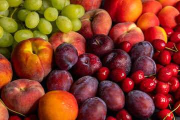 Fresh peaches, plums, cherries and grapes forming a colorful composition