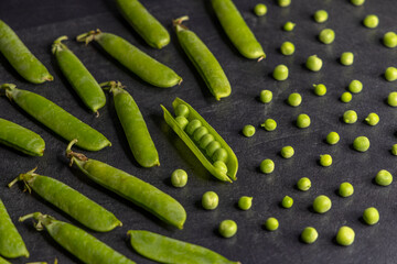 Fresh green peas arranged on a dark slate table