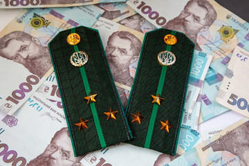Shoulder straps and patches of Ukrainian military on the background of money. War in Ukraine