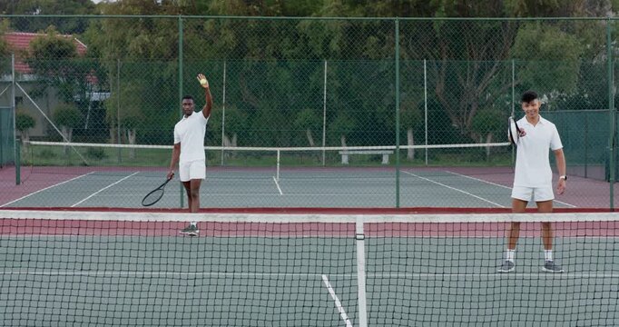 Picking up stray tennis ball at net, diverse male partners tapping strings, volleying on hard court
