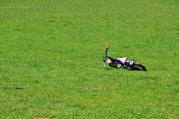Bike background. Dynamic photo of bike lies on its side alone in grassland - with free space around.