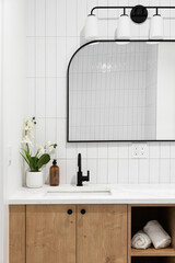 A modern farmhouse bathroom with a white oak cabinet, white marble countertop, vertical subway tile...