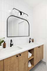 A modern farmhouse bathroom with a white oak cabinet, white marble countertop, vertical subway tile...