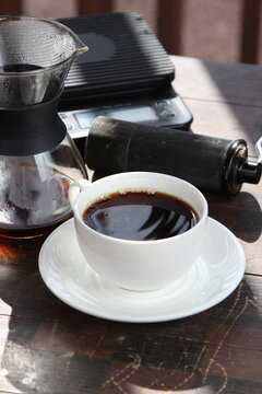 Pour-over filter dripper brewing coffee into glass Alternative coffee brewing method, pure over, teapot on wooden table

