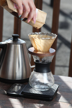 Pour-over filter dripper brewing coffee into glass Alternative coffee brewing method, pure over, teapot on wooden table


