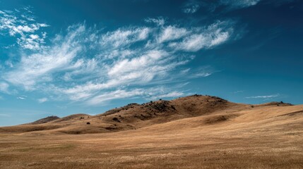Naklejka premium Vast landscape with rolling hills under a bright blue sky.
