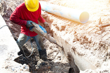 Workers use hammers to scrape away the cement layer at a construction site.