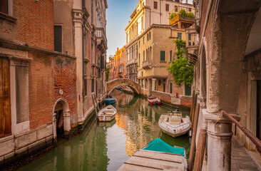 Venetian canal with stone pedestrian bridge at sunset