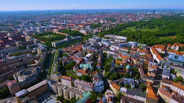 4K drone panorama of Munich with Hofgarten and the Bavarian State Chancellery, vast Englischer Garten and red-roofed Altstadt, Olympiaturm on the horizon under clear summer skies.
