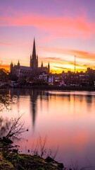 Obraz premium City cathedral reflected in a calm river at sunset