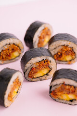 Close-up of delicious sushi rolls filled with vegetables, rice, and seaweed, served on a pastel pink background. Japanese cuisine food photography with fresh sushi maki rolls, perfect for restaurant