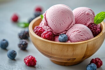 Pink ice cream scoops in a wooden bowl with berries