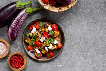  Georgian salad with deep fried eggplant, tomatoes, onions, feta cheese and cilantro on the table, copy space for text. Vegetarian food with eggplant and other vegetables, top view