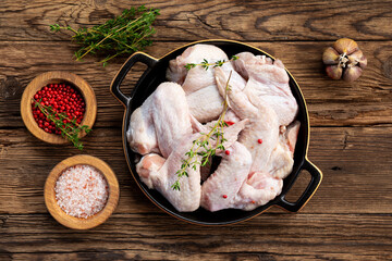Raw chicken wings and spices before cooking top view wooden background