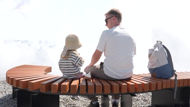 A young father with his three-year-old child daughter goes to the mountains on Rosa Khutor in Sochi in the summer. The concept of tourism, family holidays