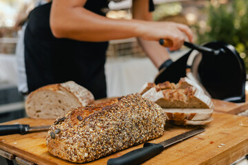 Hand-slicing craft bread on a table in a local Portuguese bakery. The healthy eating and...