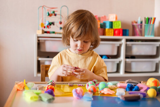 Preschool child learning through play with modeling clay - Powered by Adobe