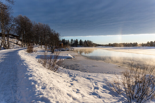 Chemin de randonn&eacute;e autour d'un lac gel&eacute; recouvert par de la brume givr&eacute;e en hiver en Laponie