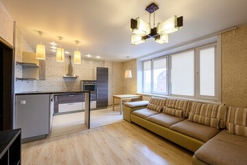 cozy, modern kitchen and living room combo, featuring a large sofa, open kitchen concept, and lots...