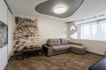 modern living room features a large snow leopard mural, a gray sectional, and a uniquely shaped...