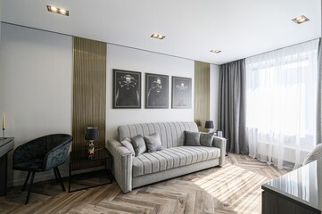 Stylish living room with a gray sofa, modern art, and natural light. The herringbone floor adds...