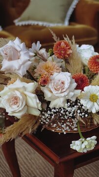 Wedding decor. Flowers in a wicker pot on a wooden table. Bouquet of flowers, roses, chrysanthemums, pampas grass at a wedding in the boho style. Close-up. Vertical video.