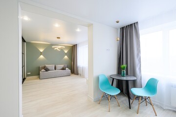 modern interior featuring an open-plan living area with a sofa, a dining nook with two chairs, and...