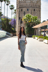 A young, beautiful Latin woman with tattoos on her arms and dressed in casual clothes walks and...