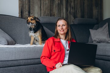 Smiling woman with dog filming on smartphone at home. Remote work, freelance lifestyle, online...