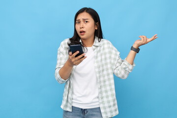 Frustrated and annoyed young Asian woman complaining after looking at mobile phone, looking...