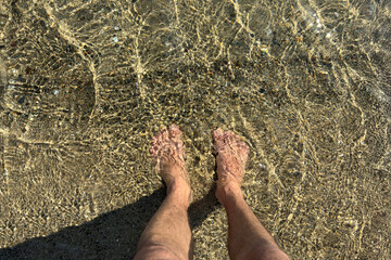 Man's Feet in Crystal Clear Shallow Water at Sandy Beach. Summer Vacation, Relaxation, Nature...