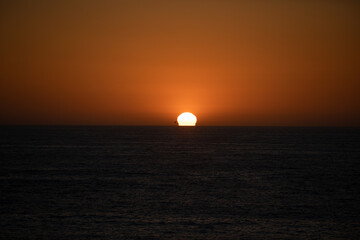 Calm sea with sunset sky and sun through the clouds over. Ocean and sky background, seascape.