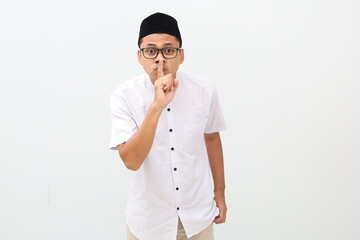 Young asian man wearing typical muslim clothes isolated on white background keeping a secret or...