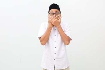 Young asian man wearing typical muslim clothes isolated on white background shocked covering mouth...
