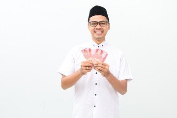 Wow excited asian muslim man standing while holding Indonesian banknotes. Isolated on white...