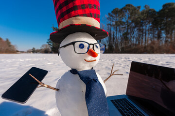 Cute snowman using phone and laptop in winter landscape. Funny snowman phone call outdoors. Snowman...