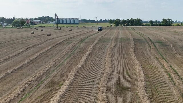 Aerial Bydgoszcz Poland farm tractor bale hay slow. Bydgoszcz a city northern Poland. Crops, wheat,  grain, potatoes and corn. Agricultural equipment. Summer growing season, autumn fall harvest. 
