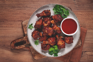 Juicy fried chicken pieces, served with spicy dipping sauce, on a rustic wooden table,