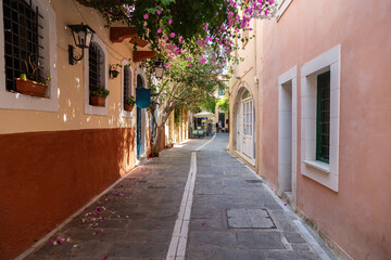 Narrow alley within Rethymno old town, Crete, pastel color walls, flowering bougainvillea, and soft shadows on stone pavement