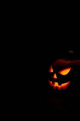 Halloween Jack-o&rsquo;-Lantern Pumpkin on Black Background with Candle Light and Copy Space