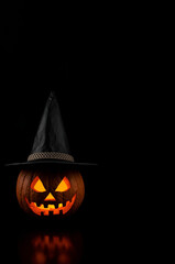Halloween Jack-o&rsquo;-Lantern Pumpkin with Witch Hat on Black Background and Copy Space.
