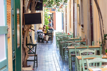 Cozy narrow alley café within Rethymno old town, Crete island, Greece. Pastel green chairs and...