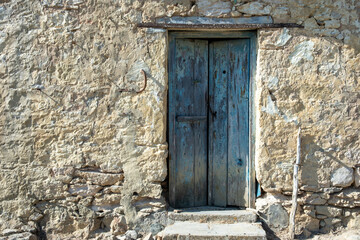 Weathered stone house with a rustic wooden door in Kastri village Gavdos island, Greece.