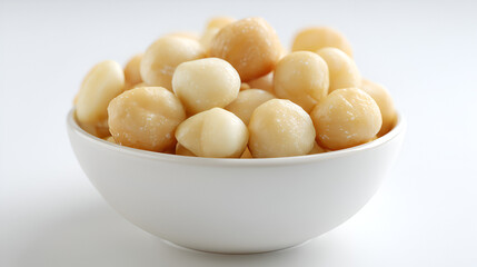 Bowl overflowing with creamy white and tan macadamia nuts, a delicious and healthy snack option.