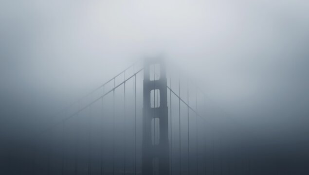 A view of the golden gate bridge partially obscured by a thick layer of dense fog and mist in the air - Powered by Adobe
